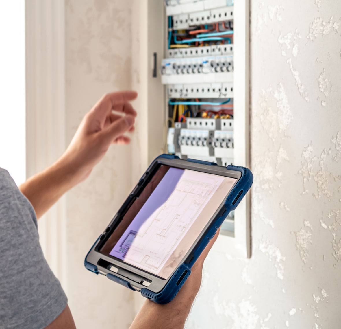 man electrical technician working switchboard with fuses uses tablet